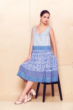 Full body slim woman in blue sundress on wooden background