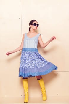 Full body slim woman in blue sundress on wooden background