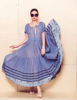 Full body slim woman in blue sundress on wooden background
