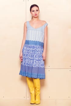 Full body slim woman in blue sundress on wooden background