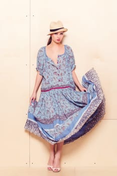 Full body slim woman in blue sundress on wooden background