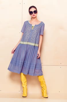 Full body slim woman in blue sundress on wooden background