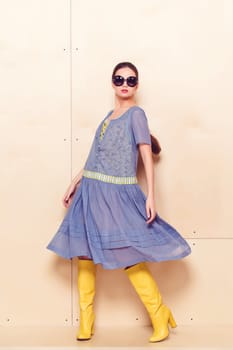 Full body slim woman in blue sundress on wooden background