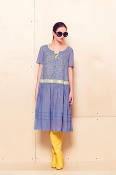 Full body slim woman in blue sundress on wooden background