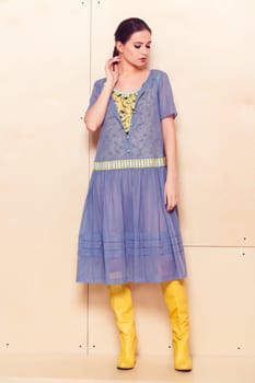 Full body slim woman in blue sundress on wooden background