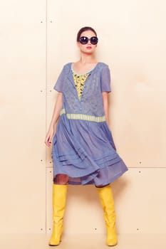 Full body slim woman in blue sundress on wooden background