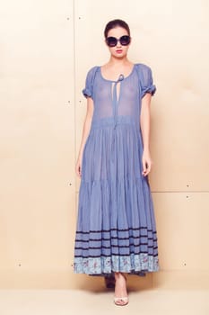 Full body slim woman in blue sundress on wooden background