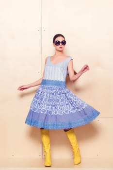 Full body slim woman in blue sundress on wooden background