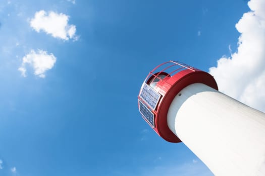 Lighthouse Photovoltaic Sky . Sea Mark at the harbor with blue sky with clouds in background