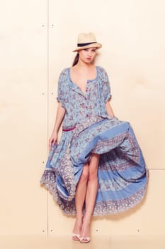 Full body slim woman in blue sundress on wooden background