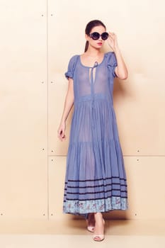 Full body slim woman in blue sundress on wooden background