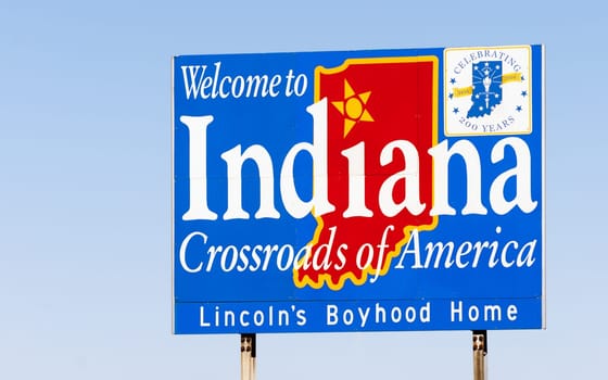Blue sign against blue sky welcomes you to Indiana