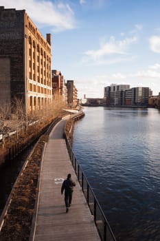 Vertical composition of man walking on a sunny spring day along the boardwalk in Milwaukee