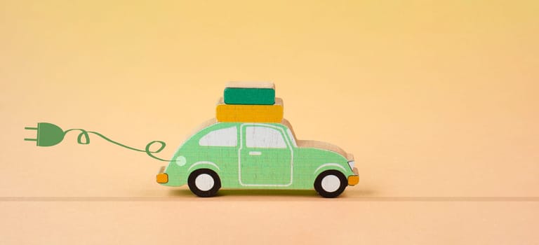 Small blue electric car with a cable for recharging, vacation trip with eco power