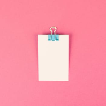 Blank white paper with a paperclip on a colored background, copy space for text, reminder or message in the office, communication concept