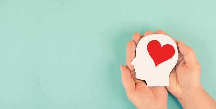 Holding a head with a red heart in the hands, symbol of love and positive emotion, charity and support