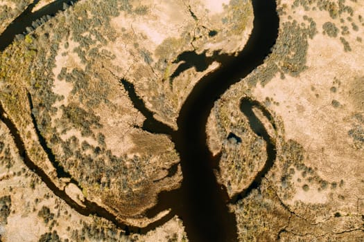 Aerial View Curved River In Early Spring Landscape. River bends and dry grass landscape. Top View Of Beautiful European Nature From High Attitude. Drone View. Bird's Eye View.