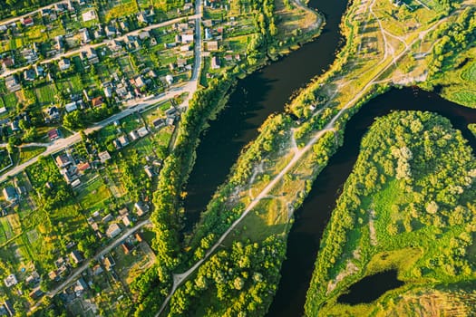 Aerial View Of Calm River And Village In Belarus, Europe. Green Forest Woods Landscape In Sunny Summer Evening. Top View Of Beautiful European Nature From High Attitude. Drone View. Bird's Eye View.