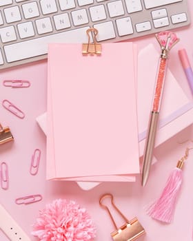 Paper with a clip, pink accessories and keyboard on pastel pink, top view, mockup. Girly workplace. Back to school concept