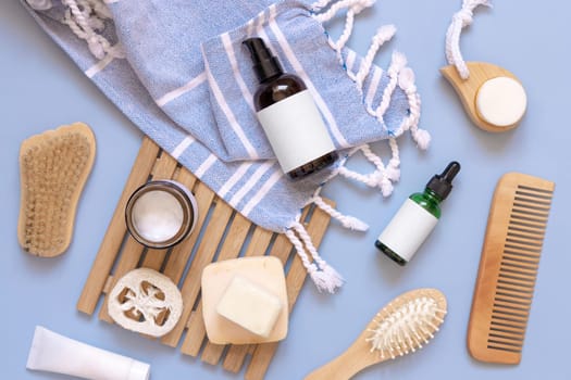 Glass one pump dispenser, skin and hair care accessories on blue bath towel top view, copy space. Packaging mockup. Natural homemade products