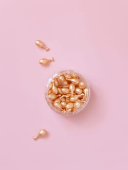 Beauty serum capsules in a jar on light pink top view. Skincare beauty product. Facial cosmetics, pastel minimal composition..