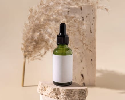 Green dropper bottle on travertine stone near dry pampas grass on light yellow, close up, mockup. Skincare beauty product. Natural cosmetics. Boho composition..