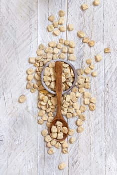 Scoop of raw dry Grass pea close up on wood. Healthy, protein source for vegan and vegetarian diet. Traditional Italian apulian cuisine ingredient. Legumes known as Cicerchia, Vetch, Blue Sweet Pea
