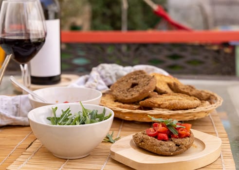 Italian appetizer Friselle with cherry tomatoes, oil and rucola served outdoor in with glasses of red wine. Tipical Apulian Dried bread, made in Salento. Local cousine. Vegetarian food