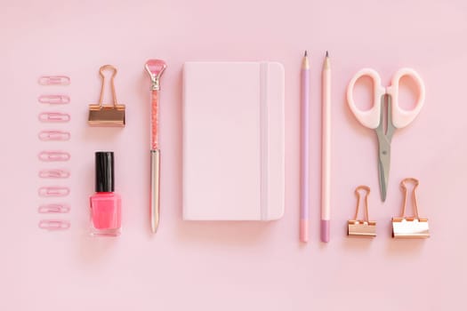 Hardcover notebook and Pink school accessories on pastel pink, Top view, textbook mockup. Girly workplace with scissors, pencils, pen, paperclips and nail polish. Back to school concept