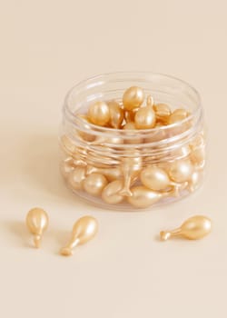Beauty serum capsules in a jar on light yellow close up. Skincare cosmetics. Facial treatment with perfect dosage of serum to be used. Pastel minimal composition..