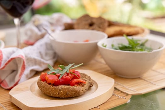 Italian summer appetizer Friselle with cherry tomatoes, oil and rucola served outdoor with glasses of red wine. Tipical Apulian Dried bread, made in Salento. Local cousine. Vegetarian food