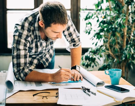 Young man working on architectural project. Modern home office concept for freelance professions.