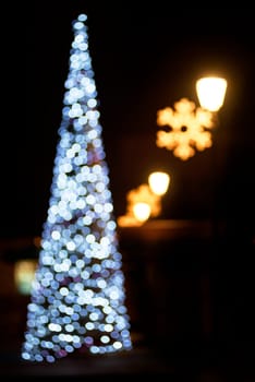 Christmas tree blur lights on christmas eve. Abstract bokeh of new years street decoration.