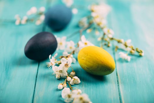 Hand painted colorful easter eggs decorated with spring cherry blossoms on wooden background.