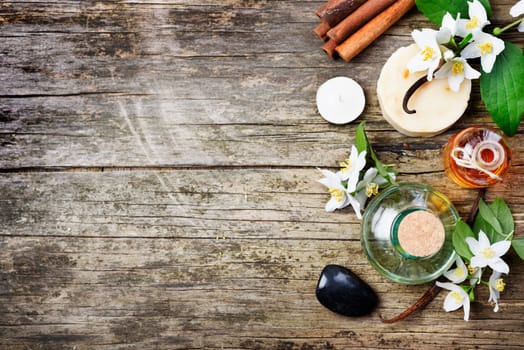 Top view of spa products with copyspace. Essential oils with jasmine, cinnamon and vanilla on grunge rustic wooden table.