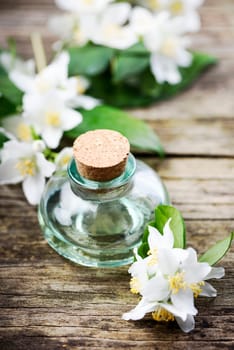 Natural homemade essential oil with jasmine flower on rustic wooden table. Spa treatment concept.