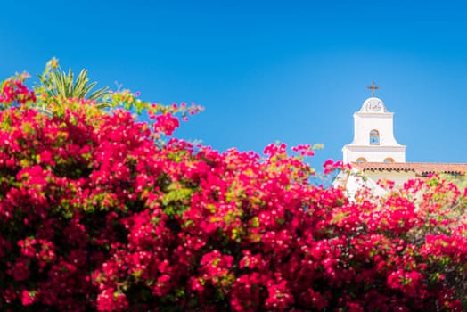 Old church in Santa Barbara county, United States of America. Blue sky in background and flowers in foreground.