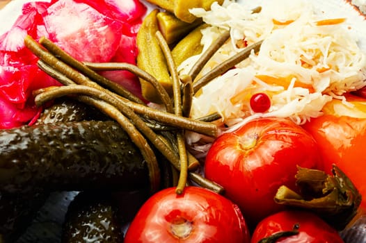 Homemade pickled cucumbers, okra, bell peppers, tomatoes and sauerkraut. Appetizing pickles, salty vegetables. Close up