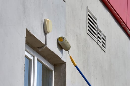 painting the street wall with a roller with gray paint. High quality photo