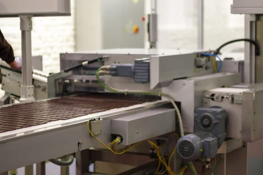 Line for the production of chocolate in an industrial factory. Automatic process in the production line of sweets. Images from the chocolate factory during production. Conveyor belt with sweets