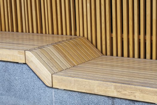 Empty modern wooden benches without people on a sunny day, public places in the city park. City improvement, urban planning, public spaces, recreation area. City public anti-vandal furniture for rest