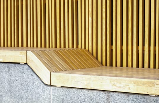 Empty modern wooden benches without people on a sunny day, public places in the city park. City improvement, urban planning, public spaces, recreation area. City public anti-vandal furniture for rest