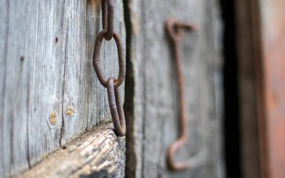 Isolated old rusty door latch on a wooden door. Close-up. Problematic weathered panels. Old wall texture background. Detail of an old wooden door with a rusty door latch