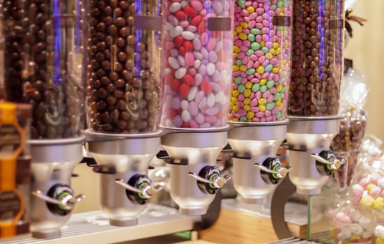 Colorful variety of fruit candies in plastic tubes in a candy store. Jelly beans for sale in the store. Colorful chewing gum balls in a pastry machine. Selective focus