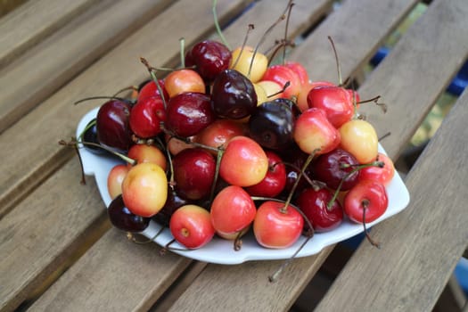 ripe sweet juicy cherries on a white dish close-up