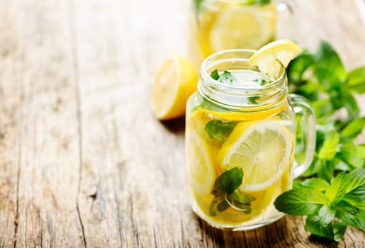 Mint lemonade in mason jars on rustic wooden table with copyspace