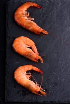 Top view of fresh shrimps on black stone slate with copyspace. Seafood ingredients  preparation.