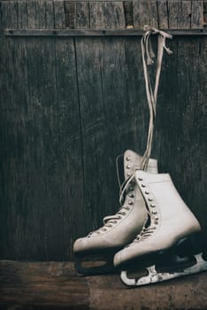 Seasonal winter holiday scene with pair of white  ice skates on rustic wooden background with copyspace.