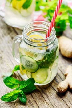 Detox drink with water, cucumber, lemonade and mint in mason jar glass with retro straws.