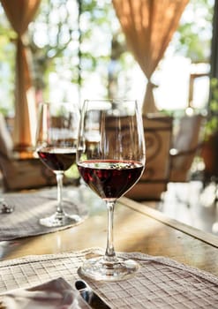 Restaurant table with two glass of red wine.